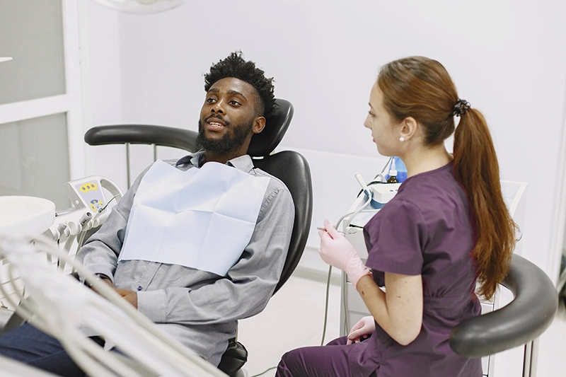 Man at dental clinic speaking with dentist